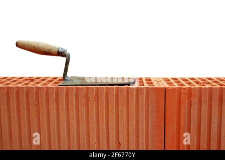 Trowel on brick wall on white background. Masonry tools. Stock Photo