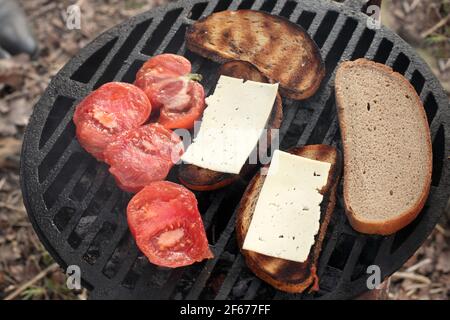 Tomatoes and bread with cheese on a barbecue grill Stock Photo