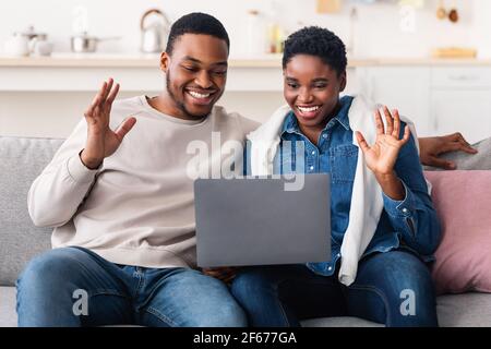 Black couple having videocall using laptop waving hands Stock Photo
