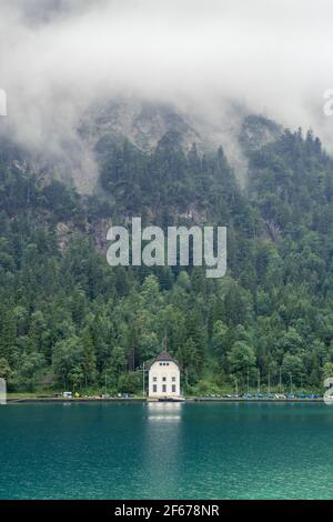 Lonely house fogy morning sunrise with lake and mountains Stock Photo