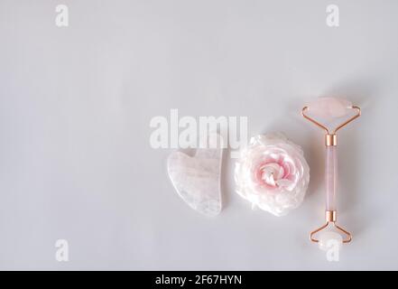 Pink Gua Sha stone and roller for massage and flower Stock Photo