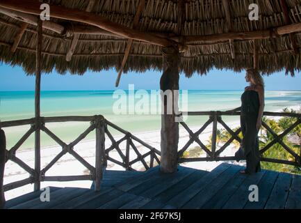 A young blonde woman standing on a wooden observation tower surveys the horizon over the Caribbean Sea on Holbox Island in Mexico. Concept travel tour Stock Photo