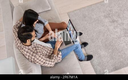 Indian couple using laptop having video call virtual meeting at home, top view. Stock Photo