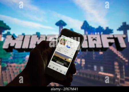 In this photo illustration, the Minecraft app in the App Store seen displayed on a smartphone screen and a Minecraft logo in the background. Stock Photo