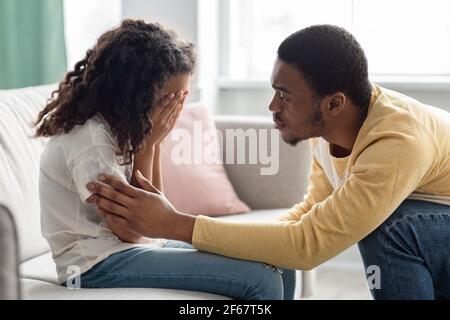 Black father comforting his crying kid, home interior Stock Photo