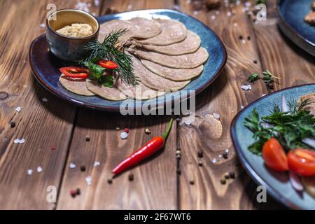 Meat and sausage cuts, garlic, chili peppers, tomatoes and other spices on a wooden brown background. Restaurant service. Stock Photo
