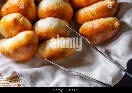 Freshly baked pies lie on a tray top view. Tweezers for buns. Stock Photo