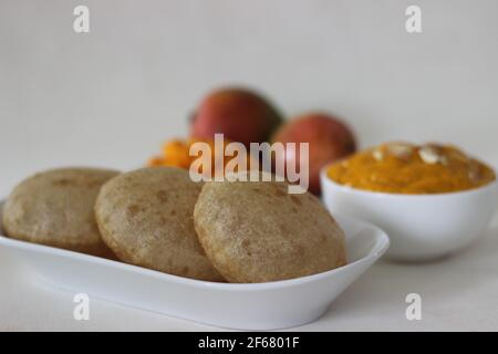 Puri served with mango pulp locally known as aamras. Mango pulp is made from Lalbagh Mango. A sweet variety from Maharashtra, India. Shot on white bac Stock Photo