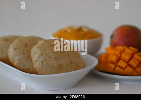 Puri served with mango pulp locally known as aamras. Mango pulp is made from Lalbagh Mango. A sweet variety from Maharashtra, India. Shot on white bac Stock Photo