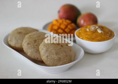 Puri served with mango pulp locally known as aamras. Mango pulp is made from Lalbagh Mango. A sweet variety from Maharashtra, India. Shot on white bac Stock Photo