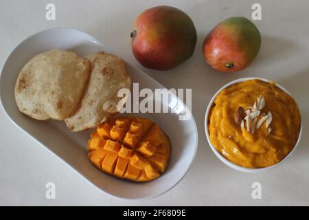 Puri served with mango pulp locally known as aamras. Mango pulp is made from Lalbagh Mango. A sweet variety from Maharashtra, India. Shot on white bac Stock Photo