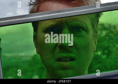 Young Man Looking Through a Pane of Green Glass Stock Photo