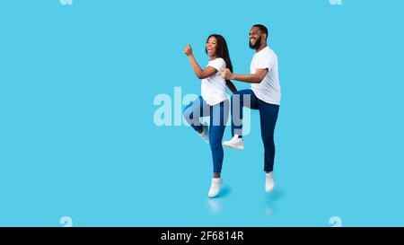 Happy young black couple walking and jumping at studio Stock Photo