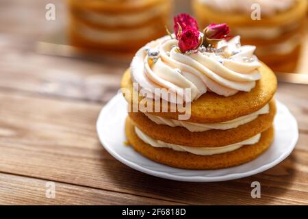 Sponge cake with cream, decorated with small flowers. The concept of a festive treat. Stock Photo