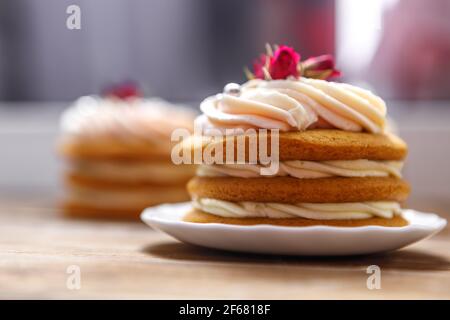 Sponge cake with cream, decorated with small flowers. The concept of a festive treat. Stock Photo