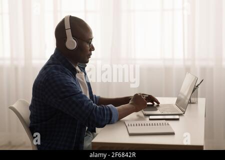 Distant work. Black mature freelancer working with laptop from home office. Man using computer for online project Stock Photo