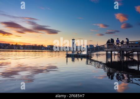 Wien, Vienna: young people on a platform at a party above oxbow lake Alte Donau (Old Danube) at fiery sunset, buildings of Donaucity, DC Tower 1, Coro Stock Photo