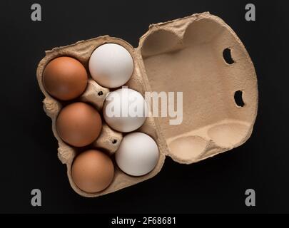 Chicken eggs, in the amount of six pieces in a disposable paper tray, on a black background, isolated Stock Photo