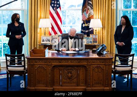 United States President Joe Biden signs the PPP Extension Act of 2021 into law in the Oval Office of the White House in Washington, DC, Tuesday, March, 30 2021. Standing at left is US Vice President Kamala Harris and at right is Isabel Guzman, Administrator, US Small Business Administration (SBA)Credit: Doug Mills/Pool via CNP/MediaPunch Stock Photo