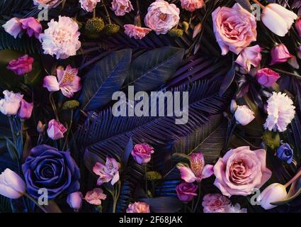 Pink neon lights  colorful flowers arrangement  with natural green  leaves. Minimal flower concept. Flat lay. Abstract floral composition. Stock Photo