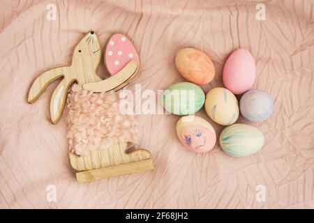 Beautiful Easter eggs, decorated with watercolors, which lie on a delicate pink fabric together with the Easter bunny. Easter and holidays concept Stock Photo