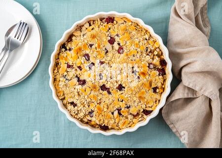 Whole apple and pear crumble with ice cream, oats streusel. Sweet dessert with stewed fruit topped crisp crumbly mixture served ice cream. Apple cobbler pie in baking dish on blue tablecloth. Top view Stock Photo
