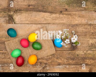 Easter colored eggs and a sprig of cherry blossoms on a wooden background. Stock Photo