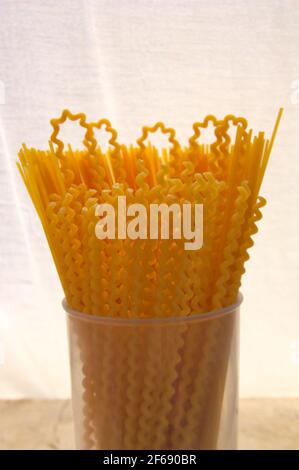 Closeup of a glass with Italian long pasta known by the name Fusilli lunghi (long spiral pasta) with white background Stock Photo