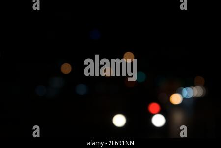 Colored circles bokeh of car lights at black dark night in city. Blurry abstract texture background. Stock Photo