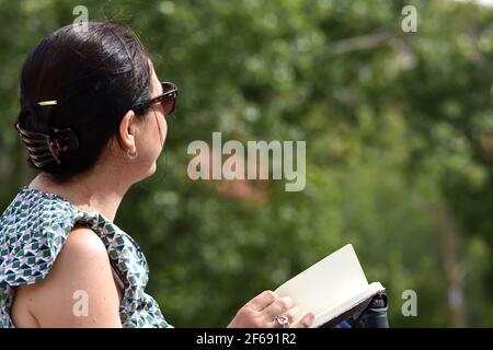 Brunette woman writing notes in a notebook among trees Stock Photo
