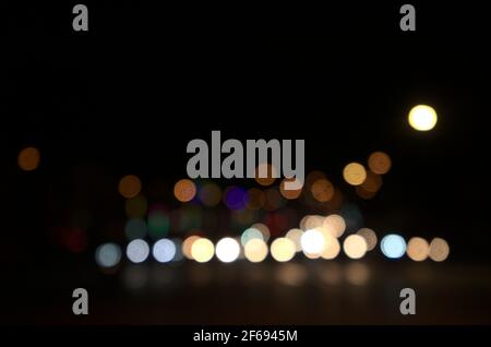 Blurry floating bokeh combination of cars on the road and street lights at the intersection, outdoor in modern big city. Beautiful blurred lights. Stock Photo