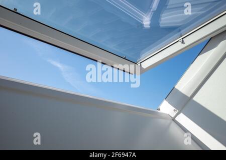 Interior view and close-up detail at open white Tilt Window Skylights at attic and background of sunny blue sky. Stock Photo