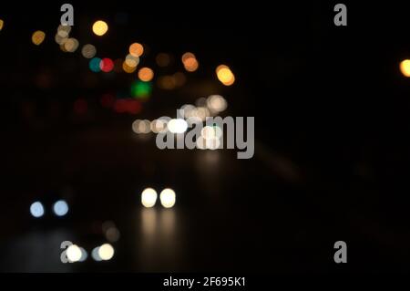 Colorful bokeh of car lights, street lights in black dark night on road in city. Blurry abstract texture background. Stock Photo