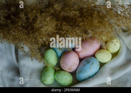 colorful Easter eggs on a light tablecloth with reeds Stock Photo