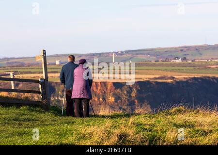 An older couple look out over Runswick Bay from Kettleness, Yorkshire Stock Photo