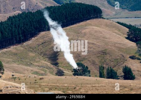 Aerial top dressing of fertilizer on hill country farmland at Otahome, near Castlepoint, Wairarapa, North Island, New Zealand Stock Photo