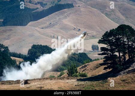 Aerial top dressing of fertilizer on hill country farmland at Otahome, near Castlepoint, Wairarapa, North Island, New Zealand Stock Photo