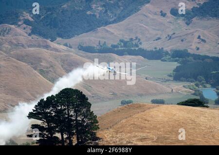 Aerial top dressing of fertilizer on hill country farmland at Otahome, near Castlepoint, Wairarapa, North Island, New Zealand Stock Photo