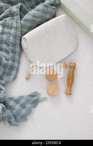 Closeup view of a toilet handbag next to a set of bamboo cosmetics for body care on a white comfortable quilt. Stock Photo
