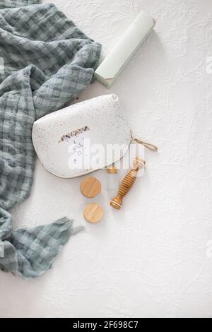 Set of bamboo cosmetics for body care next to a toilet handbag with a positive message pasted on it on a white comfortable quilt. Stock Photo