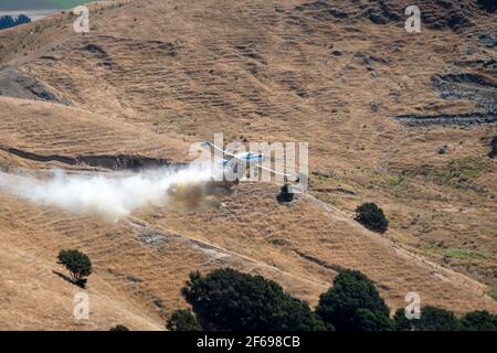 Aerial top dressing of fertilizer on hill country farmland at Otahome, near Castlepoint, Wairarapa, North Island, New Zealand Stock Photo