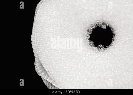 Roll of white bubble cellophane film, packaging with air bubbles close-up on a black background, isolated. Stock Photo