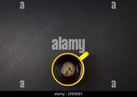 Clockwise stir. Yellow cup of black coffee flat lay on scratch rough black background. Copy space for your text, image or message. Minimal, top view. Stock Photo