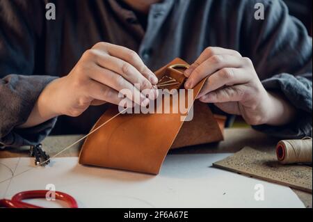 The workflow of creating exclusive leather shoes by a young craftsman in a shoe workshop. Stock Photo