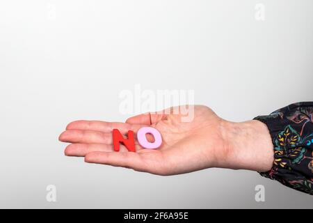 NO. Word from colorful letters of wooden alphabet on a woman's hand. Stock Photo