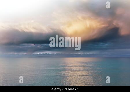 Beautiful clouds over sea. Sunlight through clouds. Beach with trees on horizon. Summer landscape. Travel background. Stock Photo