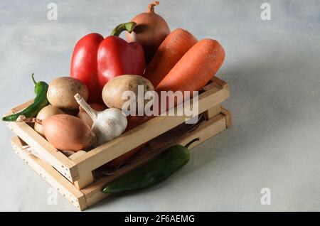 Vegetables in a wooden box. Set of vegetables, potatoes, onions, garlic, pepper, beets for cooking borscht on a textured background. Selective focus. Stock Photo