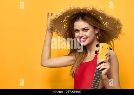 Woman holding Ukulele straw hat lifestyle Exotic yellow background Stock Photo