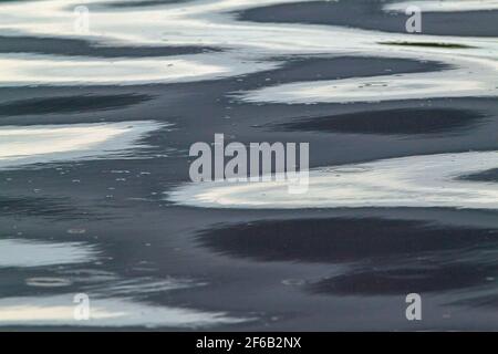 Patterns, shapes, created, formed, forming, evolving, from continuous, falling raindrops on a flowing river surface. Highlight, highlights, everchangi Stock Photo