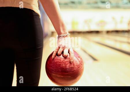 Woman throwing red bowling ball on lane closeup Stock Photo